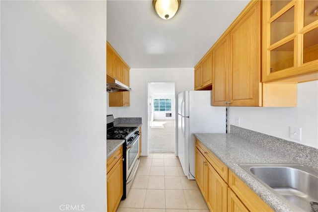 kitchen with light tile patterned floors, sink, stainless steel gas range, and white refrigerator