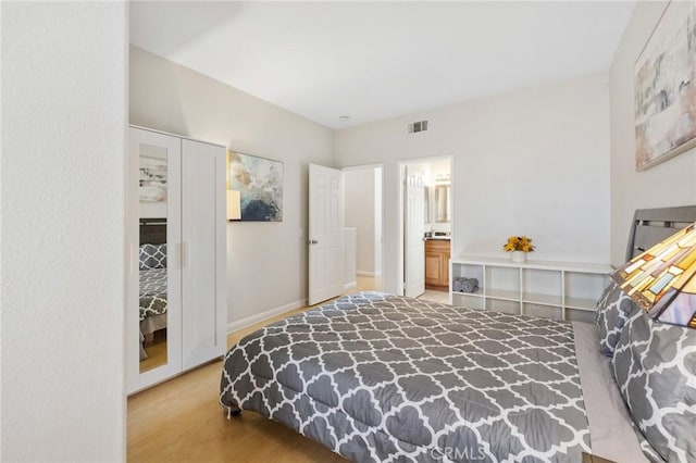 bedroom with connected bathroom and hardwood / wood-style flooring