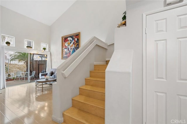 stairway with lofted ceiling and tile patterned floors