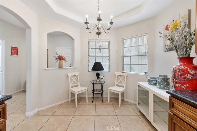 living area with a raised ceiling, light tile patterned floors, and a notable chandelier