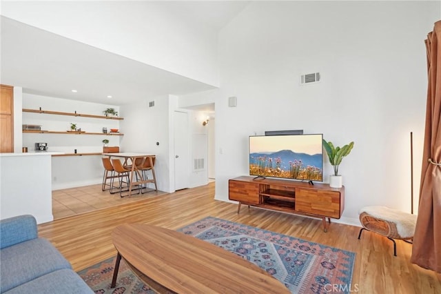 living room featuring a towering ceiling and light hardwood / wood-style flooring