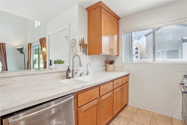 kitchen featuring light tile patterned floors, stainless steel appliances, decorative backsplash, light stone countertops, and sink