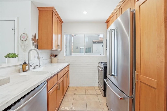 kitchen featuring stainless steel appliances, light tile patterned flooring, tile walls, light stone counters, and sink