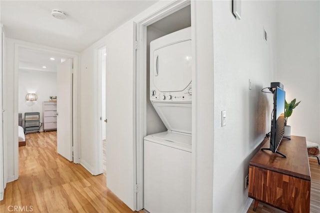 clothes washing area with stacked washer and dryer and light wood-type flooring