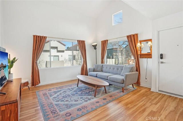 living room featuring high vaulted ceiling and light wood-type flooring