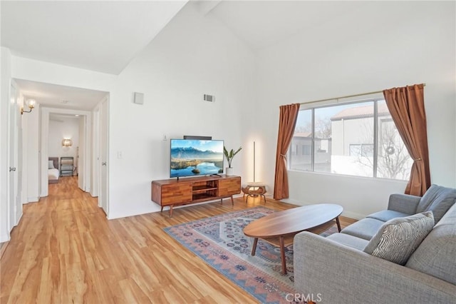 living room featuring high vaulted ceiling and light hardwood / wood-style flooring