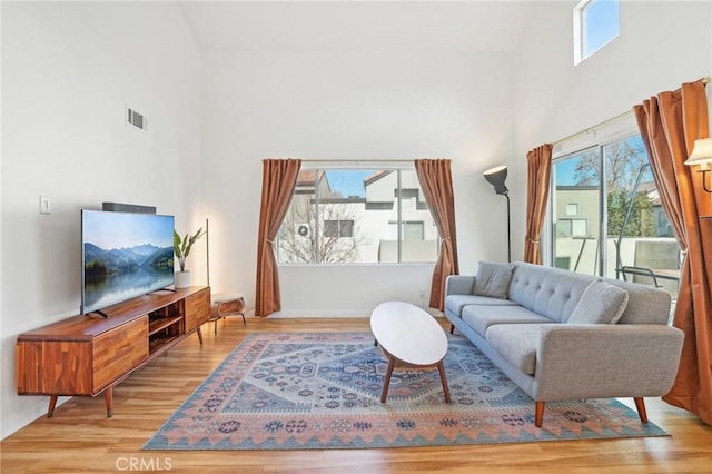 living room with light wood-type flooring and a towering ceiling