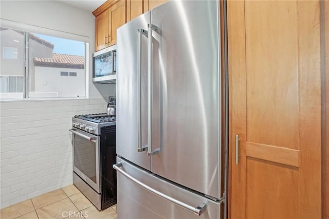 kitchen with light brown cabinetry, decorative backsplash, stainless steel appliances, and light tile patterned flooring