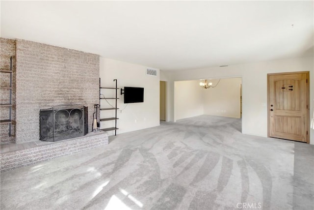 unfurnished living room with a brick fireplace, a notable chandelier, and carpet flooring