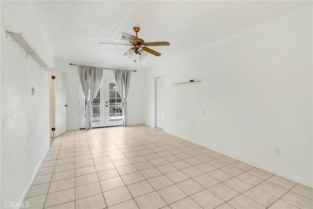 tiled spare room featuring ceiling fan and french doors