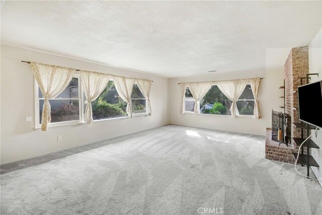 unfurnished living room with a brick fireplace and carpet