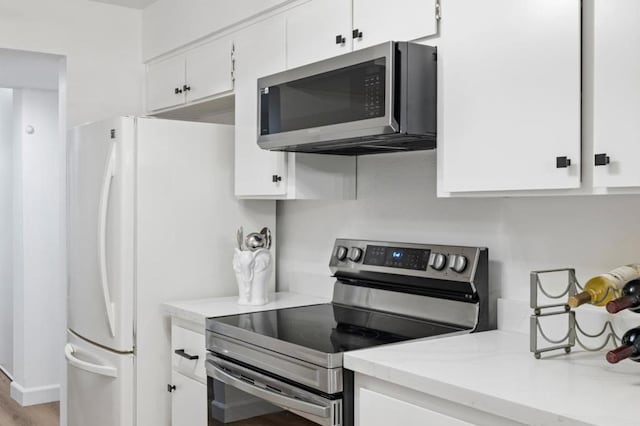 kitchen with appliances with stainless steel finishes, light hardwood / wood-style flooring, and white cabinetry