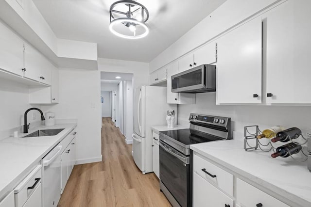 kitchen with white cabinetry, stainless steel appliances, light wood-type flooring, a chandelier, and sink