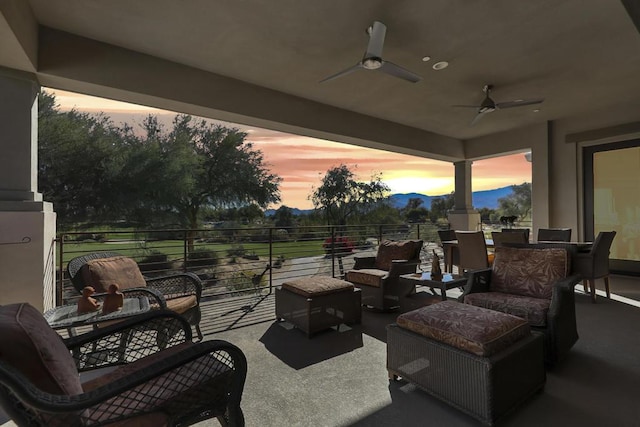 patio terrace at dusk with ceiling fan, an outdoor living space, and a balcony