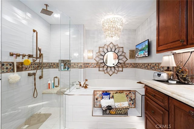 bathroom with tile walls, vanity, a chandelier, and shower with separate bathtub