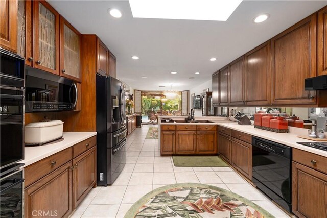 kitchen with black appliances, light tile patterned floors, kitchen peninsula, and sink