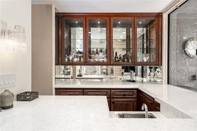 bar featuring light stone countertops and sink