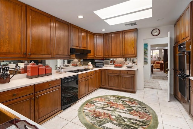 kitchen with black appliances, light tile patterned floors, and a skylight