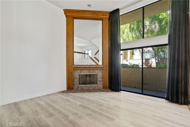 unfurnished living room with light wood-type flooring and a tile fireplace