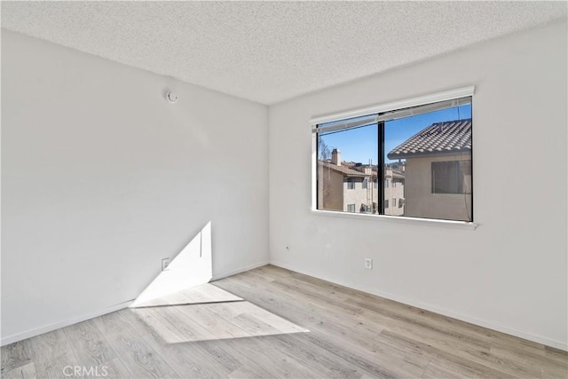 spare room featuring a textured ceiling and light hardwood / wood-style flooring