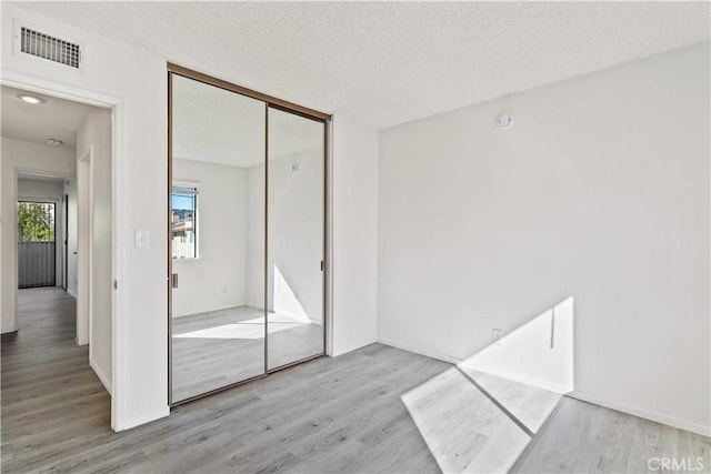 interior space with a textured ceiling and light hardwood / wood-style flooring