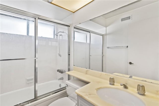 full bathroom featuring toilet, vanity, and shower / bath combination with glass door