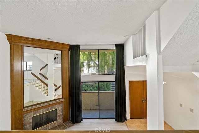 entryway featuring a healthy amount of sunlight, a tiled fireplace, and a textured ceiling