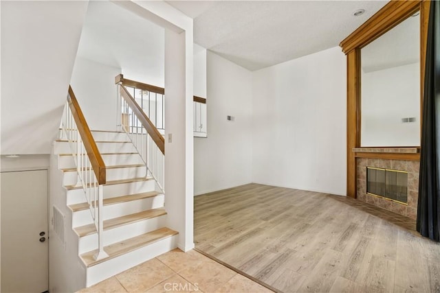 staircase with a tile fireplace and hardwood / wood-style flooring