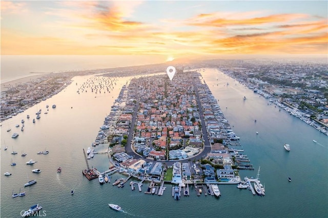 aerial view at dusk with a water view and a view of the beach