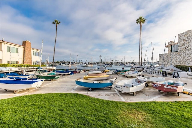 view of parking / parking lot with a lawn and a water view