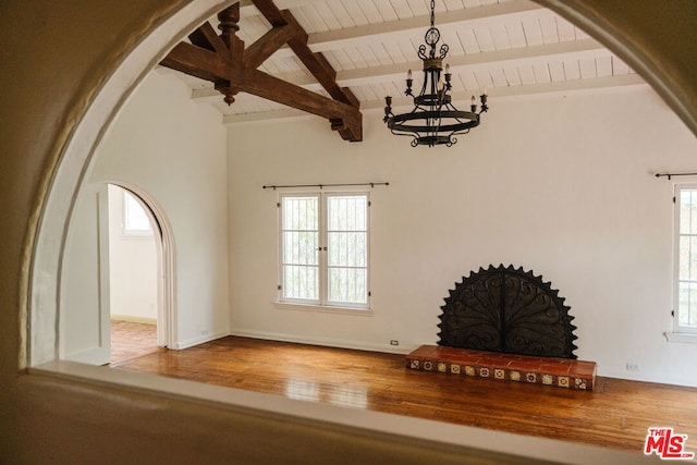 unfurnished living room featuring wooden ceiling, a chandelier, a wealth of natural light, and beamed ceiling