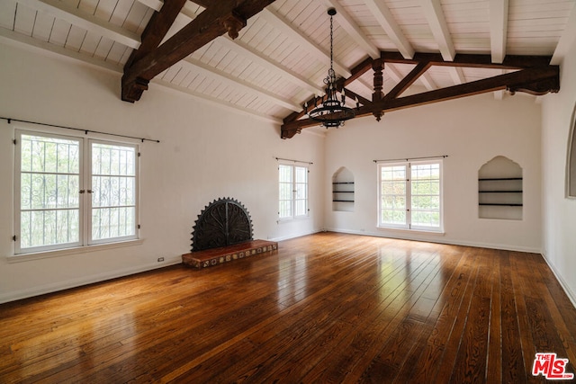 unfurnished living room with a brick fireplace, beam ceiling, an inviting chandelier, hardwood / wood-style flooring, and high vaulted ceiling