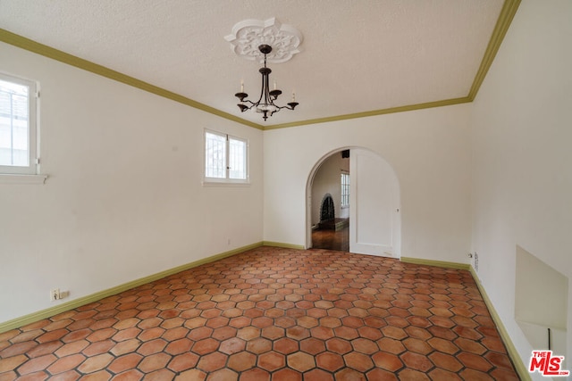 spare room with a textured ceiling, crown molding, and a notable chandelier