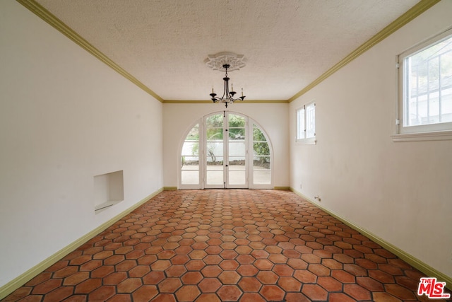 spare room featuring a textured ceiling, ornamental molding, and a notable chandelier