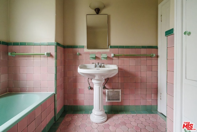 bathroom featuring a bath, tile patterned flooring, and tile walls