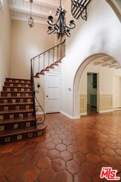 stairway featuring wooden ceiling, beam ceiling, and an inviting chandelier