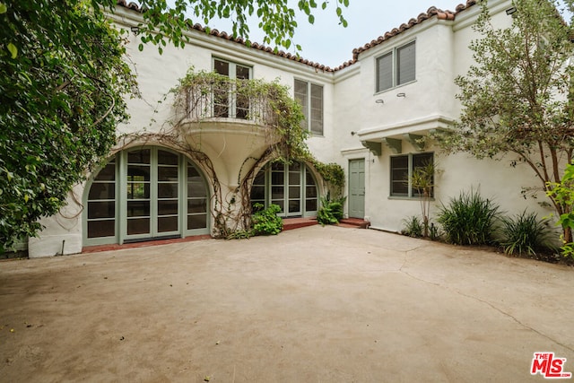 rear view of house featuring a balcony and a patio