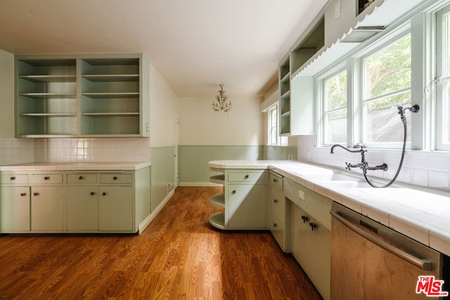 kitchen with tile counters, dark hardwood / wood-style floors, tasteful backsplash, dishwasher, and sink