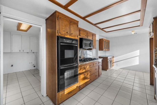 kitchen featuring black double oven, stainless steel gas cooktop, tasteful backsplash, and light tile patterned floors