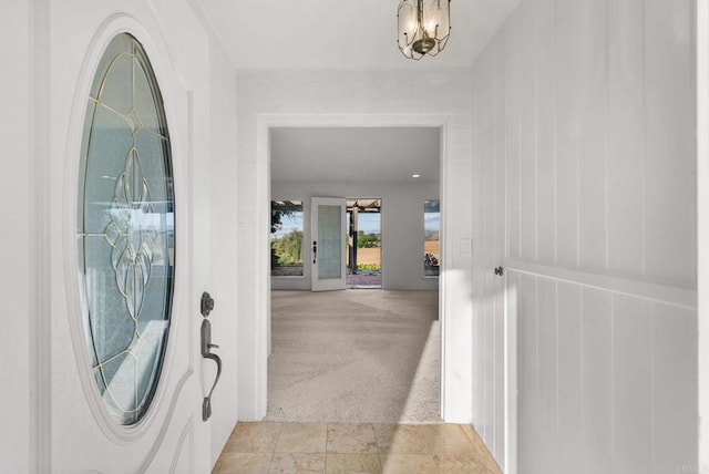 carpeted foyer entrance with a notable chandelier