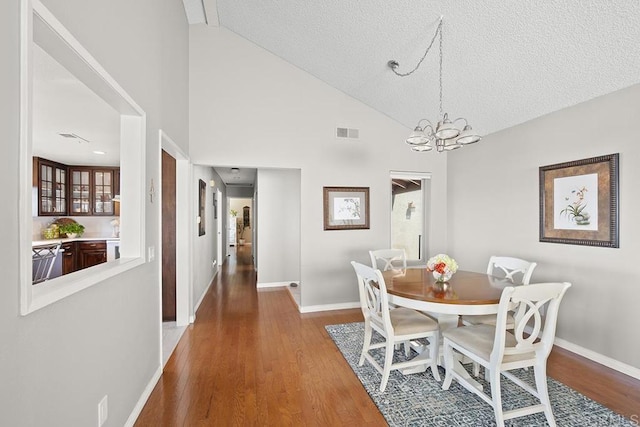 dining space featuring hardwood / wood-style flooring, a chandelier, high vaulted ceiling, and a textured ceiling