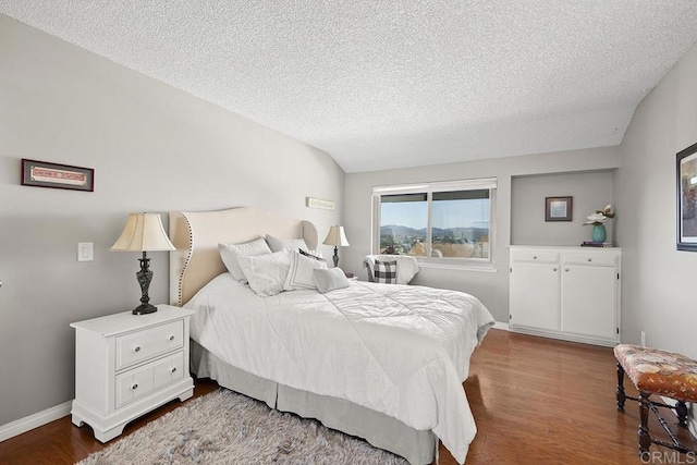 bedroom with lofted ceiling, wood-type flooring, and a textured ceiling