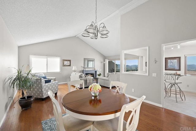 dining space featuring lofted ceiling, wood-type flooring, a chandelier, and a textured ceiling