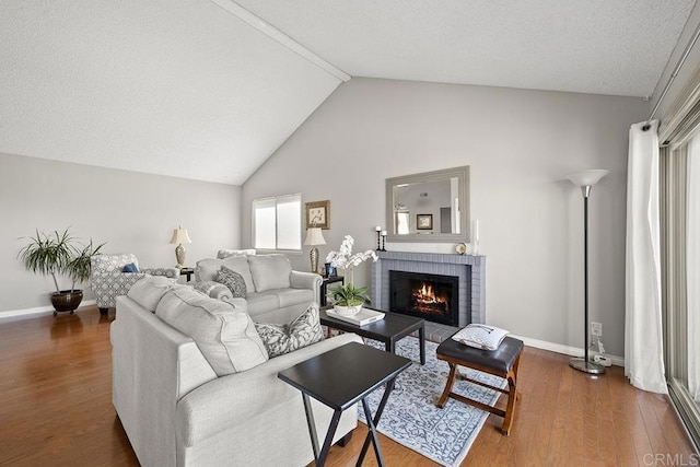 living room featuring vaulted ceiling, a brick fireplace, and dark hardwood / wood-style flooring