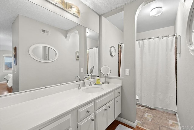 bathroom featuring vanity, toilet, and a textured ceiling