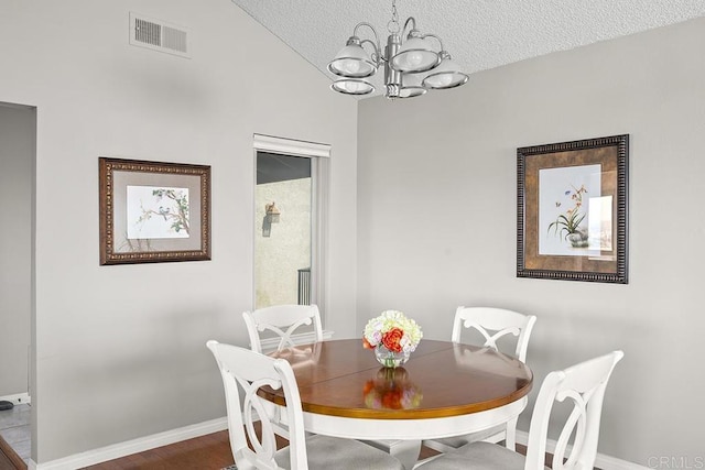 dining space featuring an inviting chandelier, hardwood / wood-style flooring, lofted ceiling, and a textured ceiling