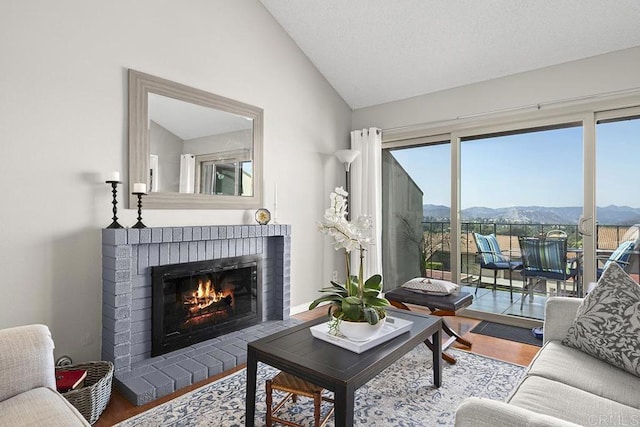 living room featuring a mountain view, vaulted ceiling, a healthy amount of sunlight, and a brick fireplace