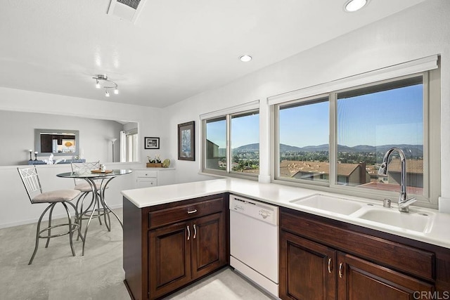 kitchen with dishwasher, sink, dark brown cabinetry, kitchen peninsula, and a mountain view