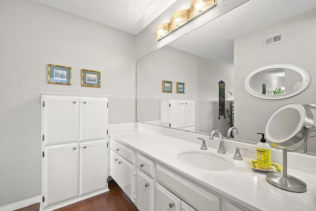 bathroom featuring hardwood / wood-style flooring, vanity, and a textured ceiling