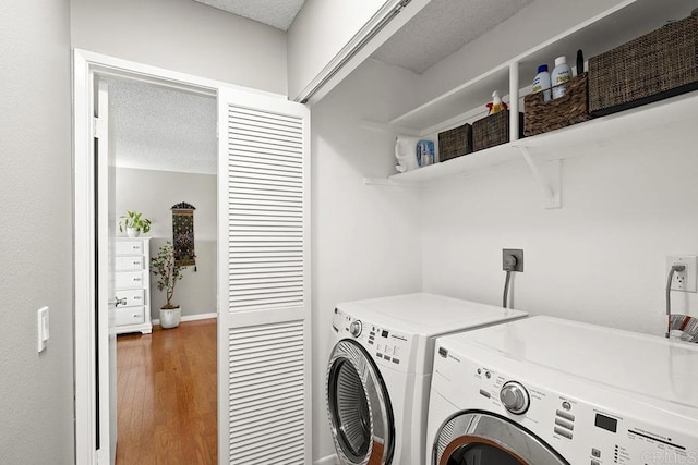 clothes washing area with hardwood / wood-style flooring, a textured ceiling, and independent washer and dryer